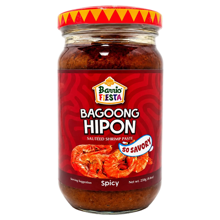 A glass jar of Barrio Fiesta Bagoong Hipon (spicy salted shrimp paste) on a white background. The jar has a red label with a picture of cooked shrimp and a red lid with a yellow and orange pattern.