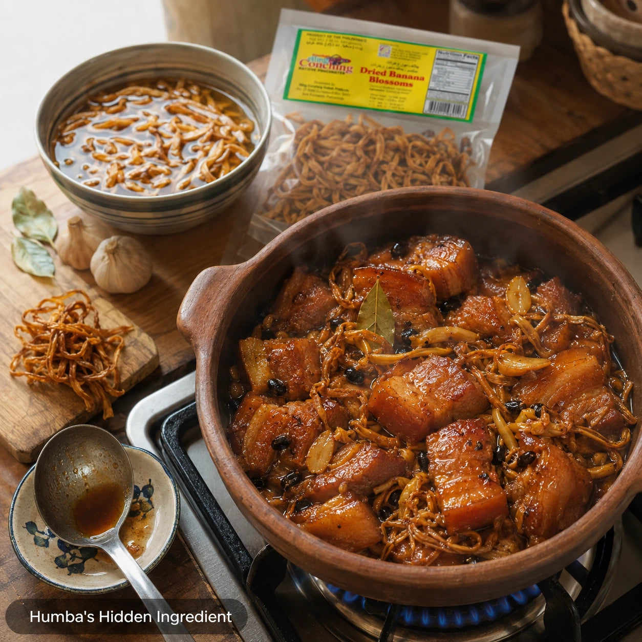 Aling Conching Dried Banana Blossom soaking in a bowl beside garlic, bay leaves, and a bubbling pot of Cebuano-style humba on the stove