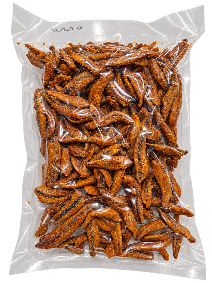 A clear plastic bag filled with roasted, reddish-brown snack pieces, photographed on a plain white background. The bag has a printed brand name near the top edge.